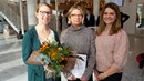 Tre kvinnor står med diplom och blommor