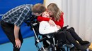 En man och en kvinna kramar om en pojke som sitter i rullstol