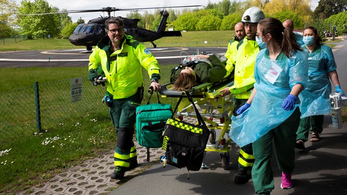 Vårdpersonal rullar in en skadad patient från en helikopter i bakgrunden, som en del i en katastrofövning