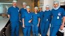 En grupp människor i blå operationskläder står tillsammans