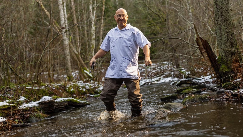 En man i vårdbussarong vadar i en bäck