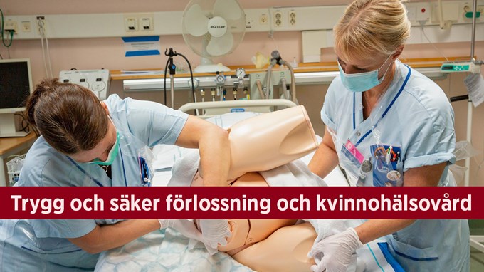Två kvinnor i vårdkläder tränar förlossningsarbete på en docka