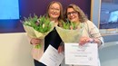 Två kvinnor med diplom och blommor.