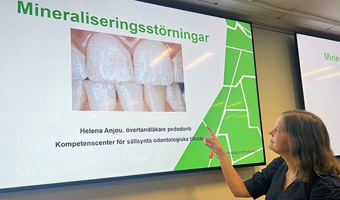 Kvinna som föreläser om mineraliseringsstörningar framför en skärmbild som visar framtänder.