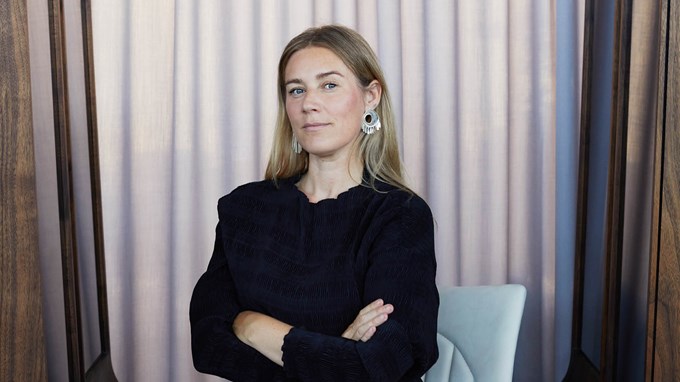 Yngre kvinna i svarta kläder står med armarna i kors.