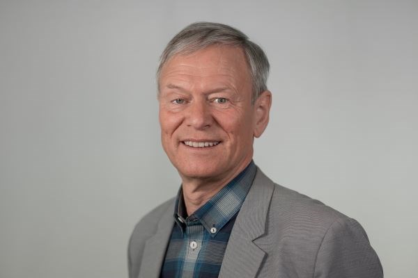 Porträttbild på Rolf Fredriksson, leende och klädd i blågrårutig skjorta och grå kavaj.
