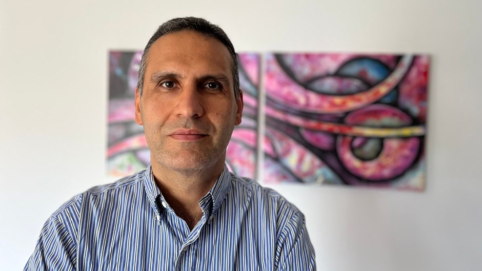 En man i skjorta tittar mot kameran.