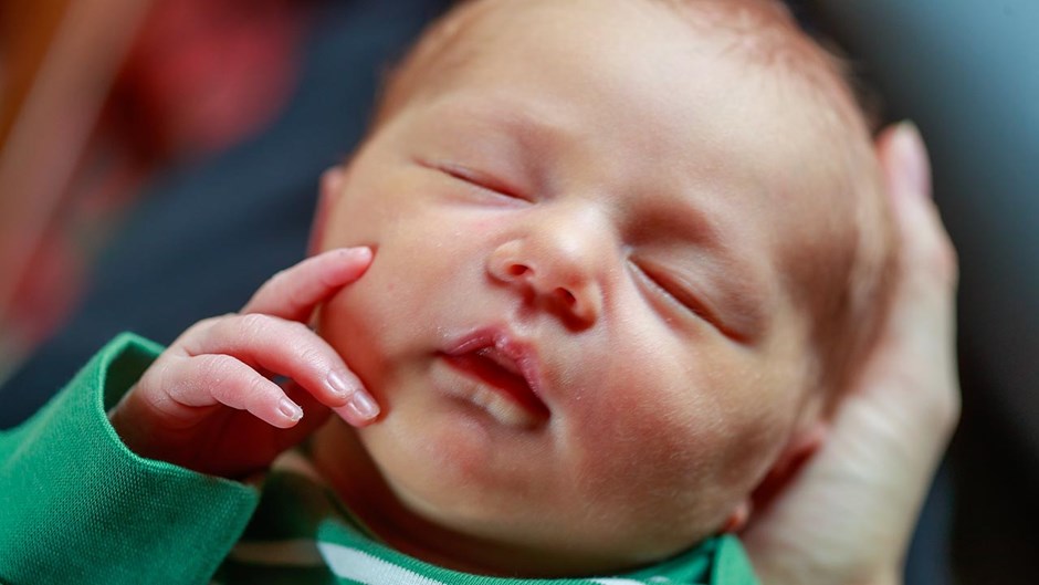 Nyfödd bebis i grön tröja.