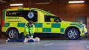 En person utför hjärt- och lungräddning på en docka. I bakgrunden syns en ambulans.