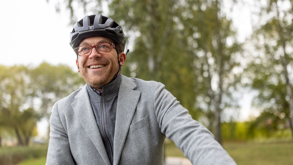 Man med cykelhjälm iklädd kavaj i en grönskande miljö