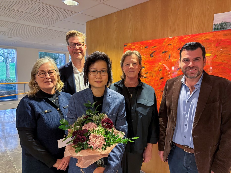 Fem personer på rad och en blombukett.