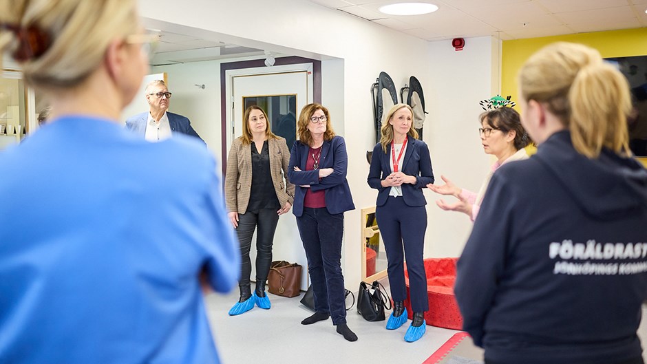 En grupp människor som lyssnar på en kvinna som berättar om verksamheten.
