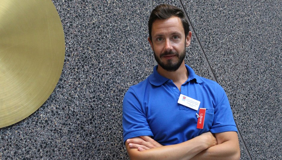 En skäggprydd man i blå piketröja håller armarna i kors.