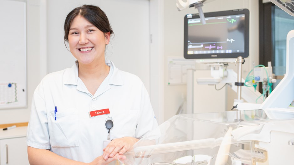 Kvinna i vita sjukvårdskläder som står i ett patientrum.