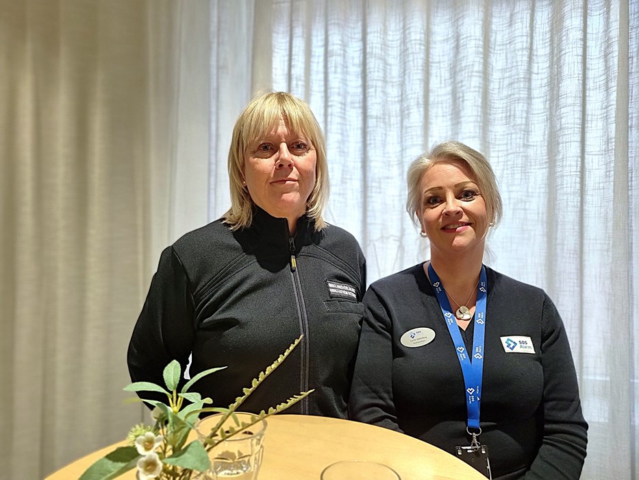 Två kvinnor i mörka kläder med namnbrickor står sida vid sida.