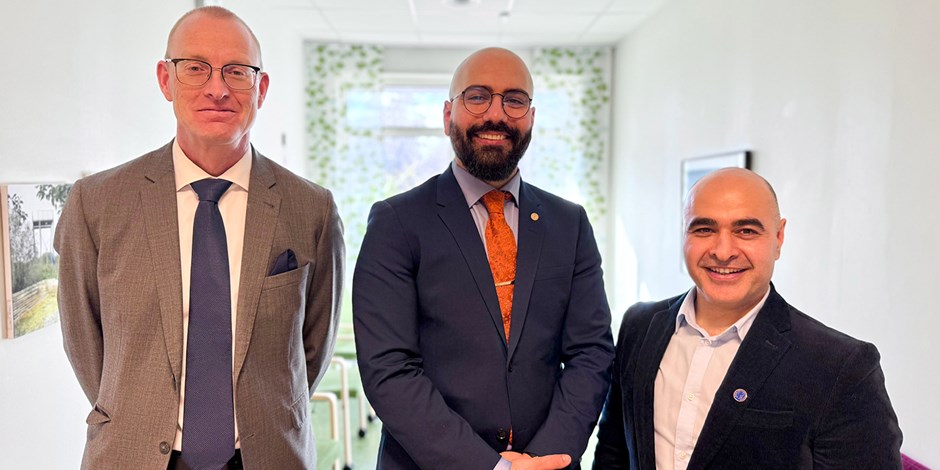 Tre män i kostym står uppradade och ler in i kameran.