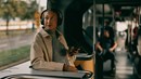 En ung kvinna med hörlurar tittar ut genom ett bussfönster.