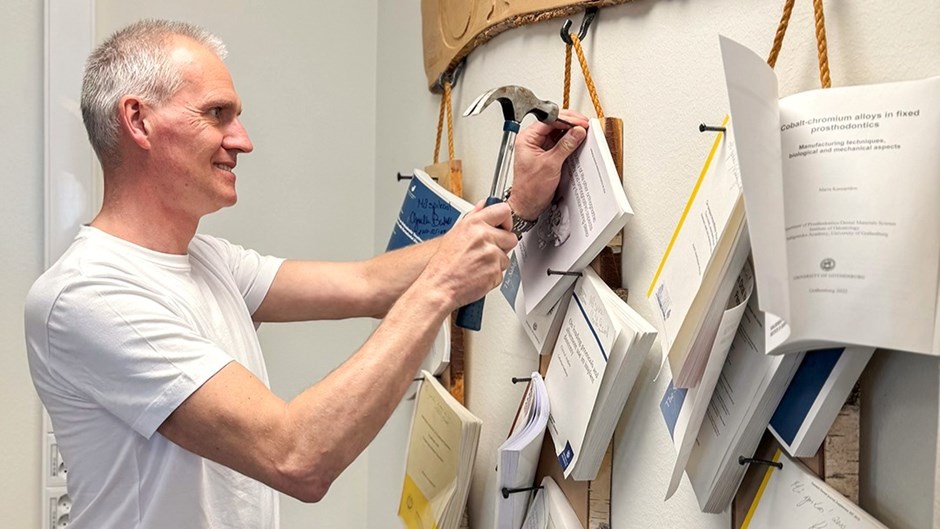 En man i vit t-shirt spikar upp sin doktorsavhandling på väggen.