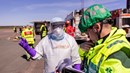 En man i vita sjukvårdkläder står och pratar med en person som har ambulanskläder på sig.