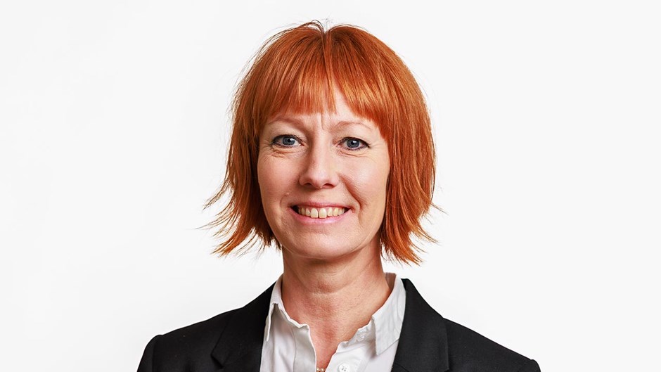 En kvinna tittar in i kameran och ler.