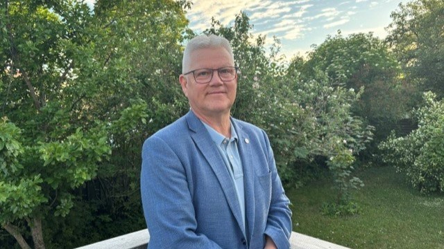 En man står utomhus. Han tittar in i kameran.