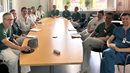 Många personer i sjukvårdskläder sitter runt ett konferensbord.