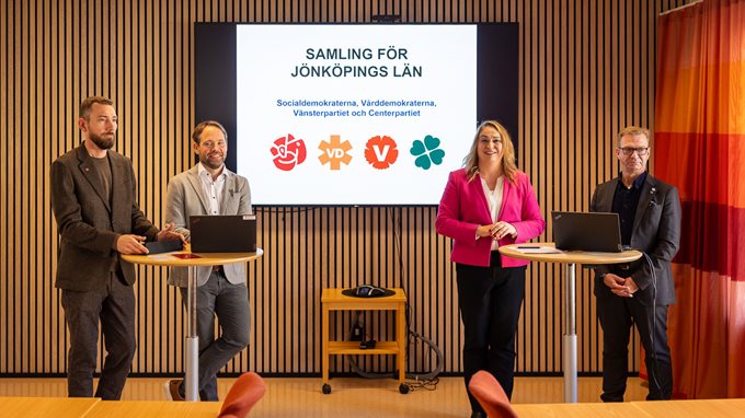 Fyra personer står vid två ståbord och håller en presskonferens.